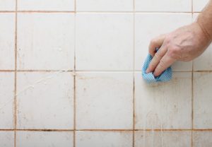cleaning dirty shower and  bathroom tiles with mould